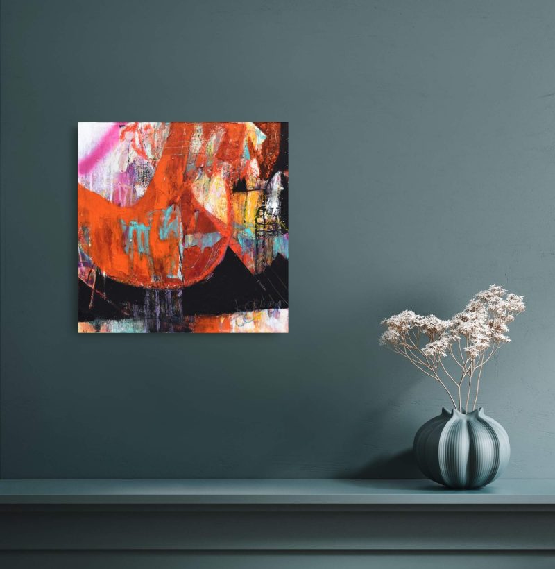 An orange, white, black, pink, and teal mixed media abstract painting titled "Heavy is the Head" by Kathryn Gruber hangs on a dark teal background above a shelf. To the right is a vase of the same colour with some small white flowers in it.